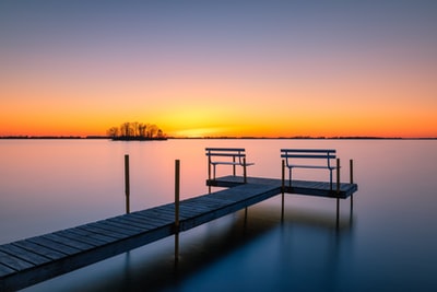 日落时在水体上的褐色木质船坞